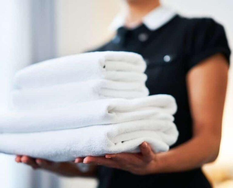early american motel worker holding freshly cleaned and folded towels