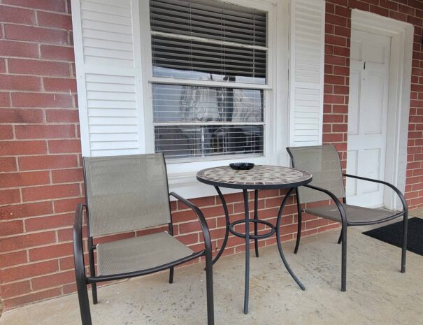 Early American Motel Deluxe King covered porch with table and two chairs