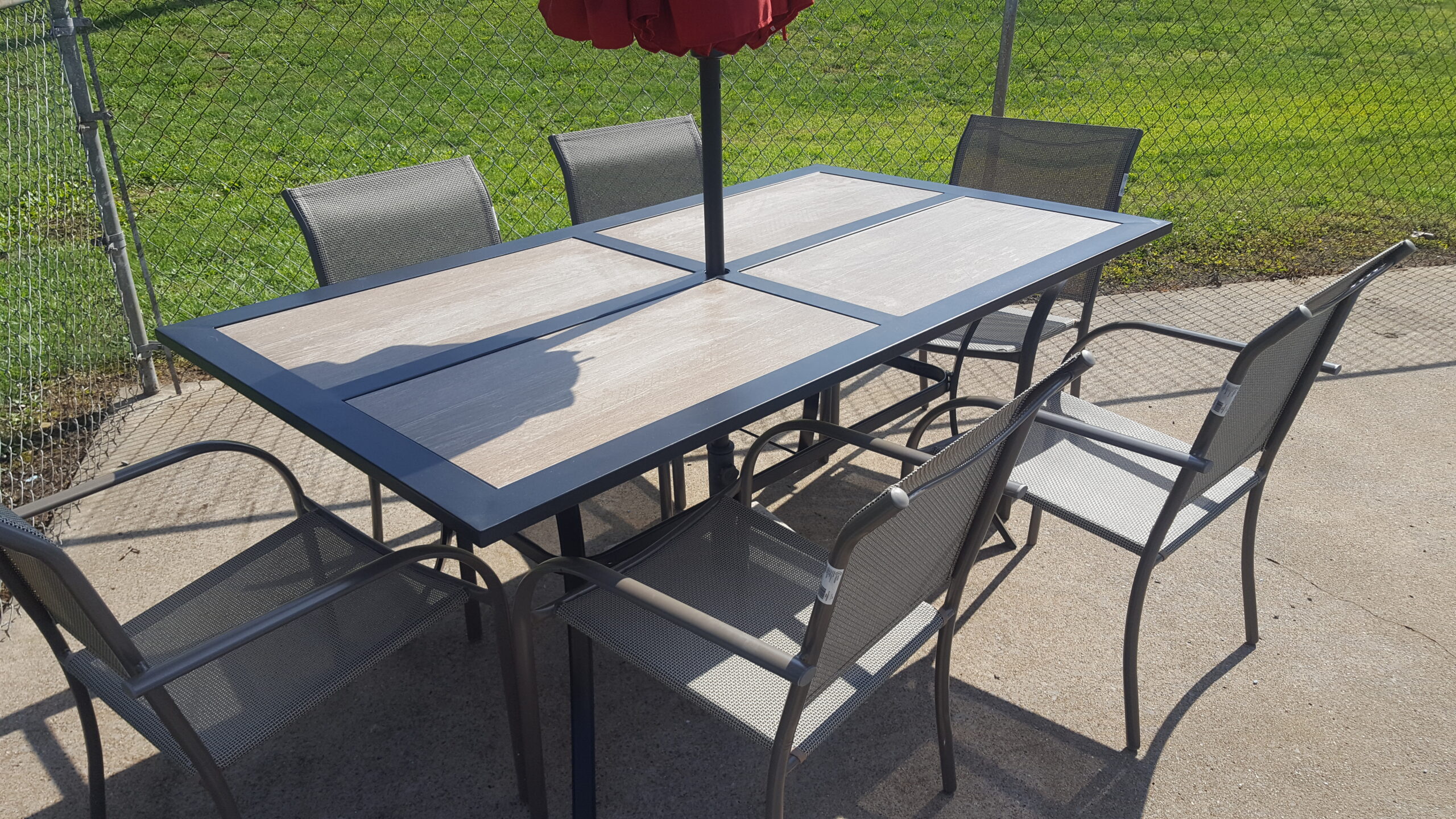 Outdoor patio table and chairs beneath a red umbrella at Early American Motel