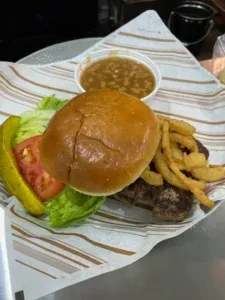 A burger with fries, fresh toppings and a side dish