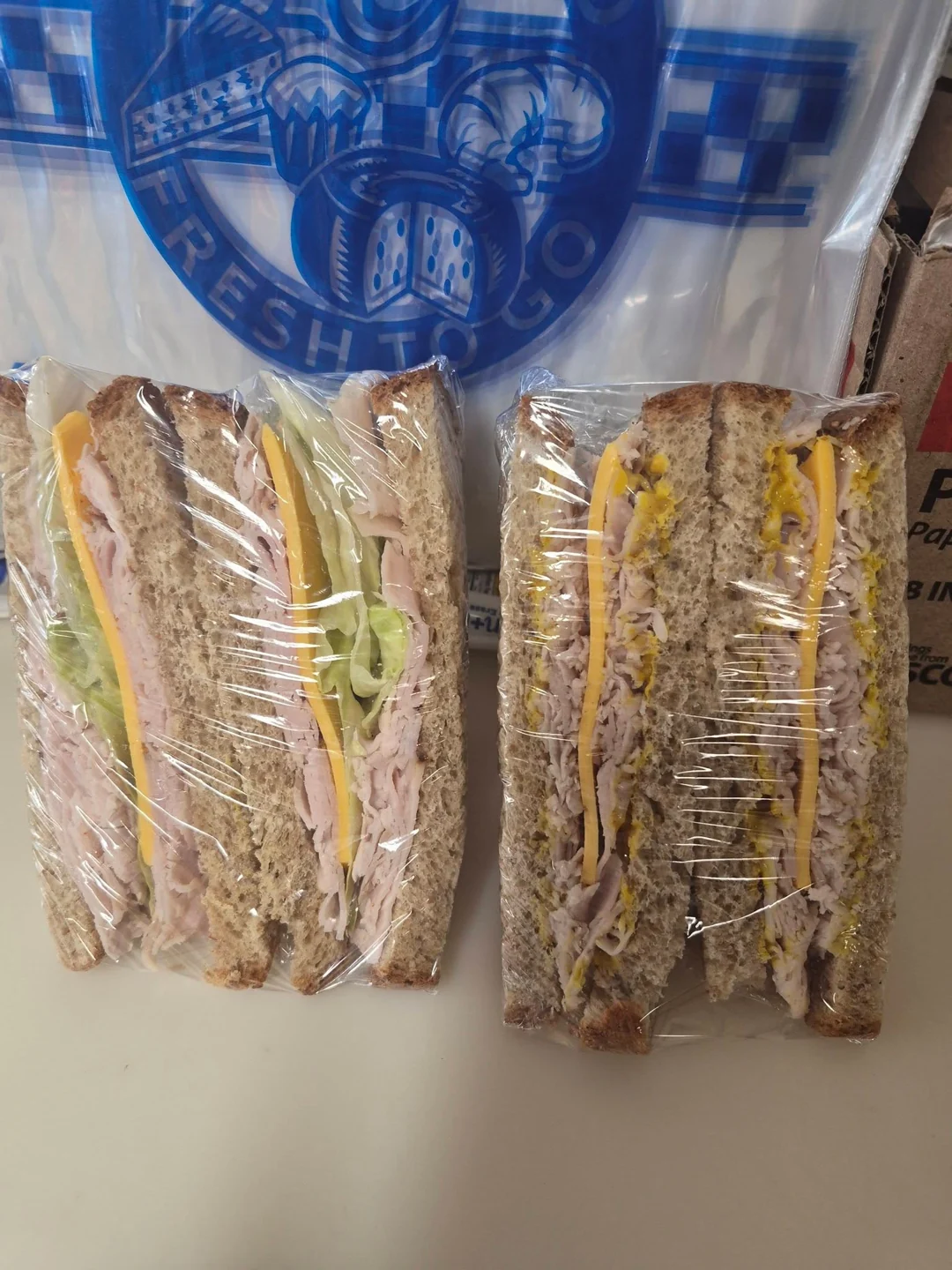 Wrapped sliced-bread sandwiches with meat, cheese and lettuce