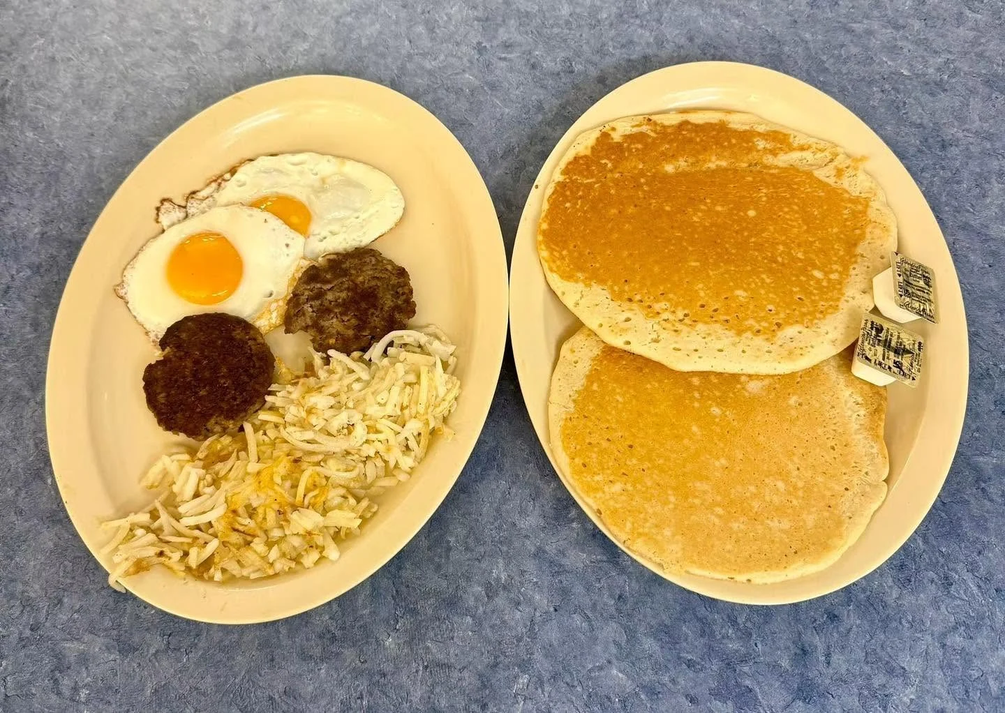 Eggs, sausage patties and hash browns beside a plate of pancakes at Deaton’s Cafe