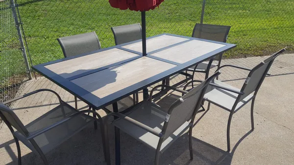 Outdoor patio table and chairs beneath a red umbrella at Early American Motel